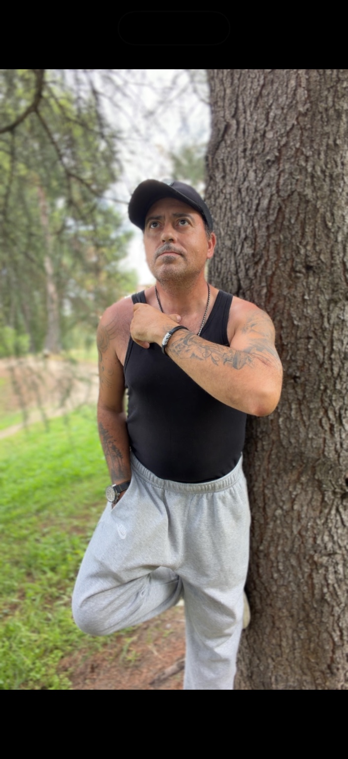 Retrato de Antonio Ortega junto a un árbol.